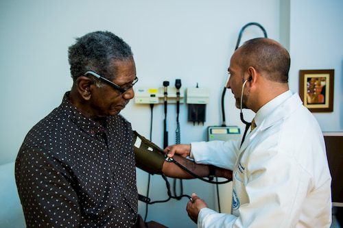 male physician taking a male patient’s blood pressure